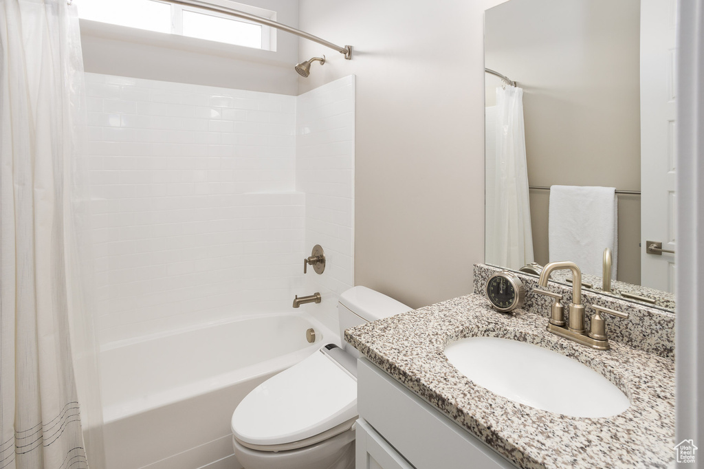 Full bathroom featuring shower / bath combo with shower curtain, toilet, and oversized vanity