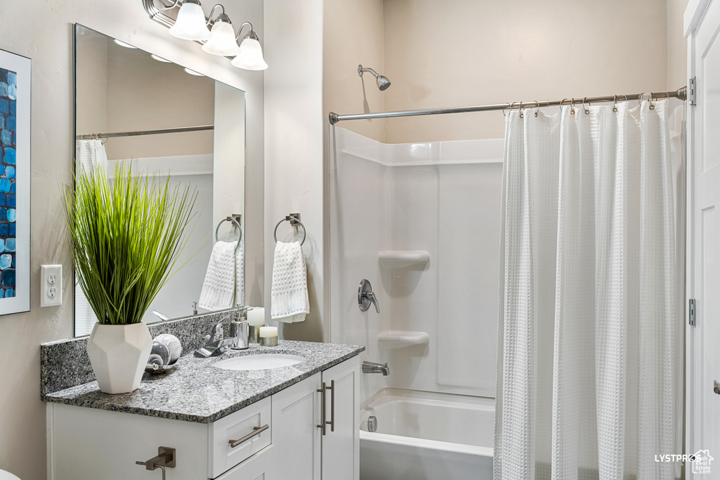 Bathroom with vanity with extensive cabinet space and shower / bathtub combination with curtain