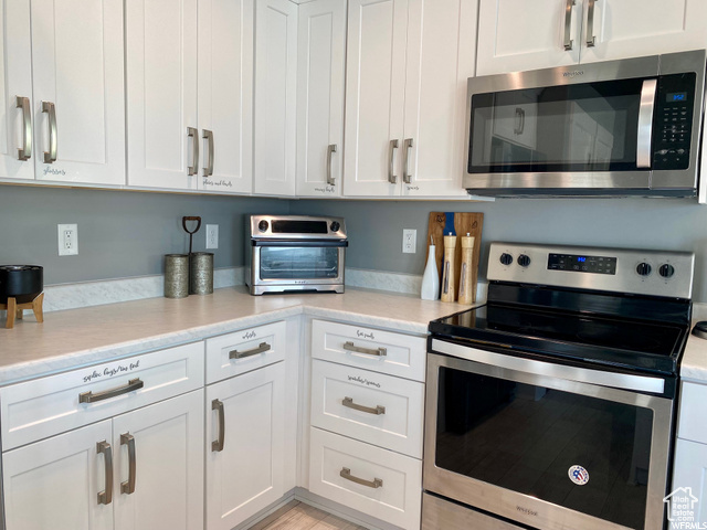 Kitchen with appliances with stainless steel finishes and white cabinetry