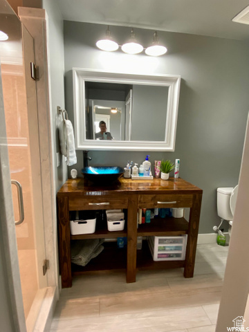 Bathroom with an enclosed shower, toilet, and hardwood / wood-style floors