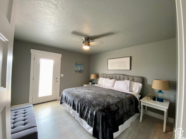 Bedroom featuring light hardwood / wood-style floors, a textured ceiling, ceiling fan, and access to outside