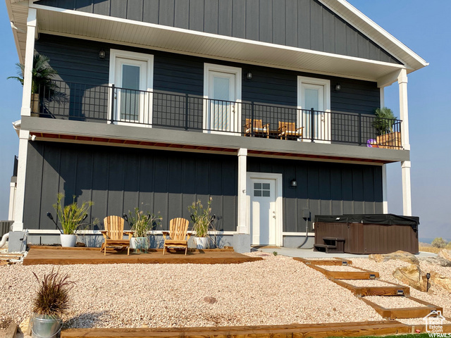 View of front of property featuring a balcony, a patio, and a hot tub
