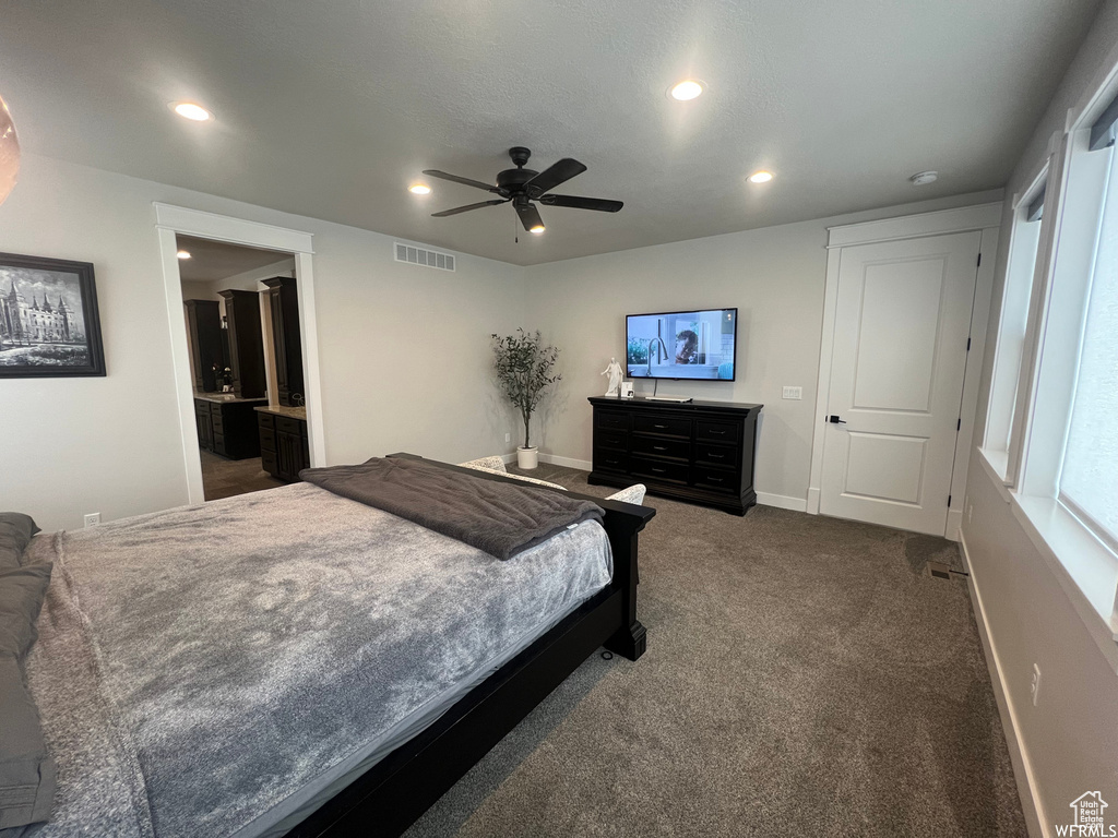 Carpeted bedroom featuring ensuite bathroom and ceiling fan
