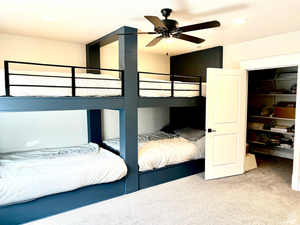 Unfurnished bedroom with a spacious closet, a closet, light colored carpet, and ceiling fan