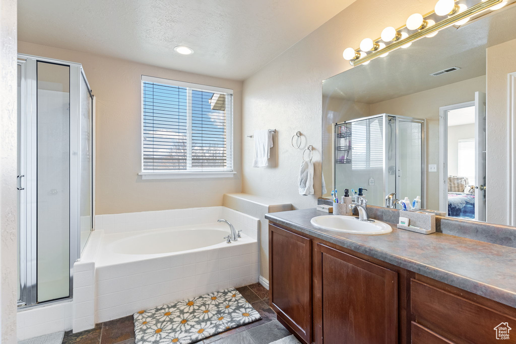 Bathroom with separate shower and tub, tile flooring, a wealth of natural light, and vanity