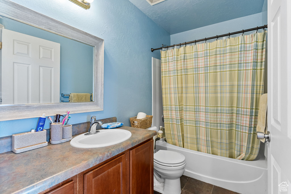 Full bathroom featuring toilet, tile floors, shower / tub combo with curtain, and vanity