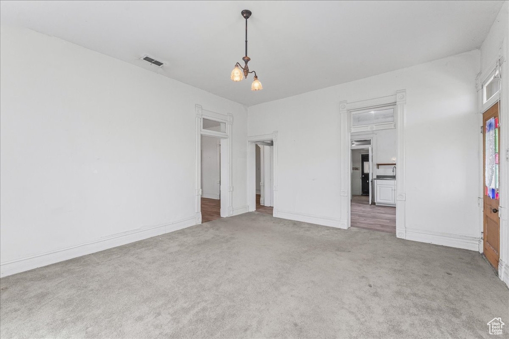 Empty room featuring carpet flooring and a notable chandelier