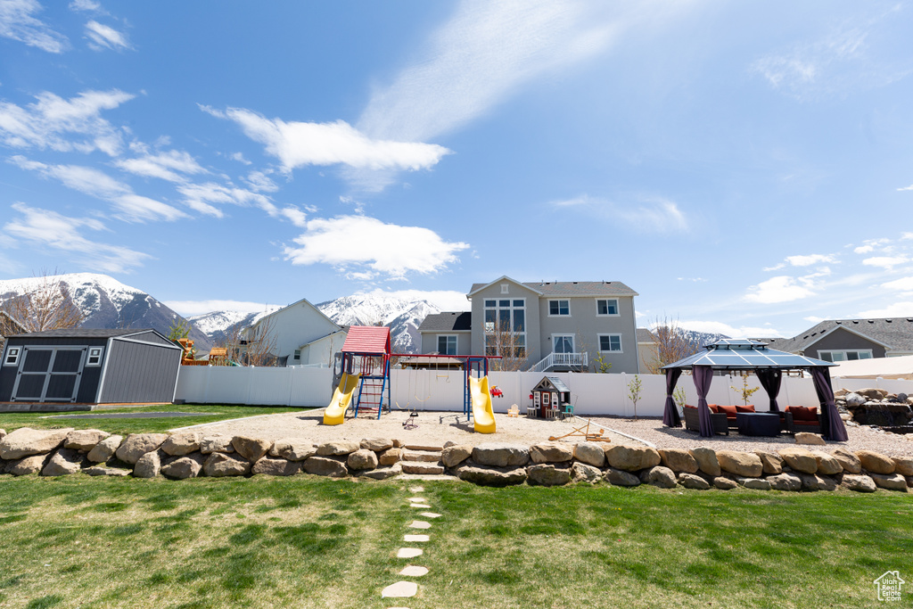 View of yard featuring a mountain view, a playground, a gazebo, and a storage unit