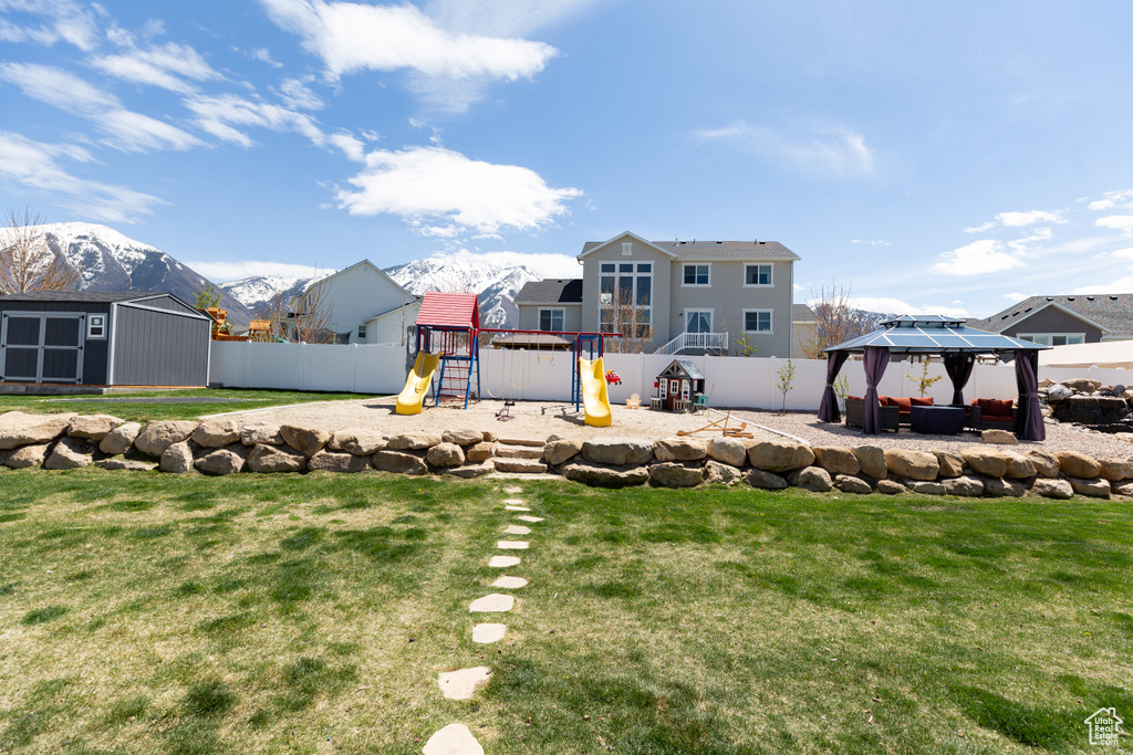View of yard with a mountain view, a shed, a playground, and a gazebo