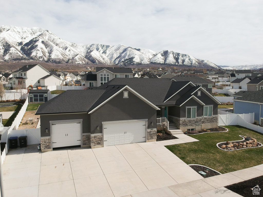 View of front of home with a front lawn, a garage, and a mountain view
