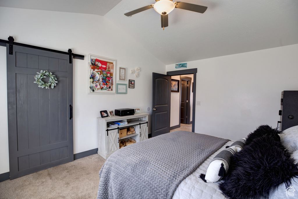 Bedroom featuring light colored carpet, a barn door, ceiling fan, and lofted ceiling