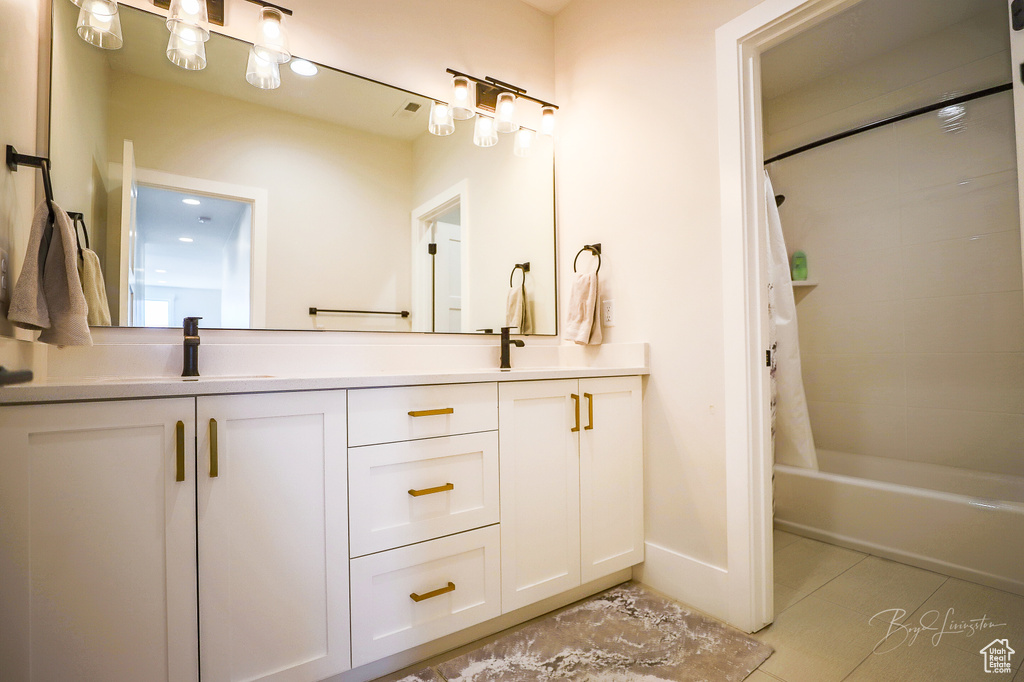 Bathroom featuring shower / tub combo with curtain, double sink, tile floors, and vanity with extensive cabinet space