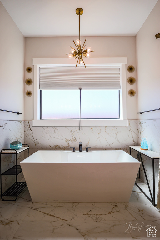 Bathroom featuring a healthy amount of sunlight, tile floors, tile walls, and an inviting chandelier