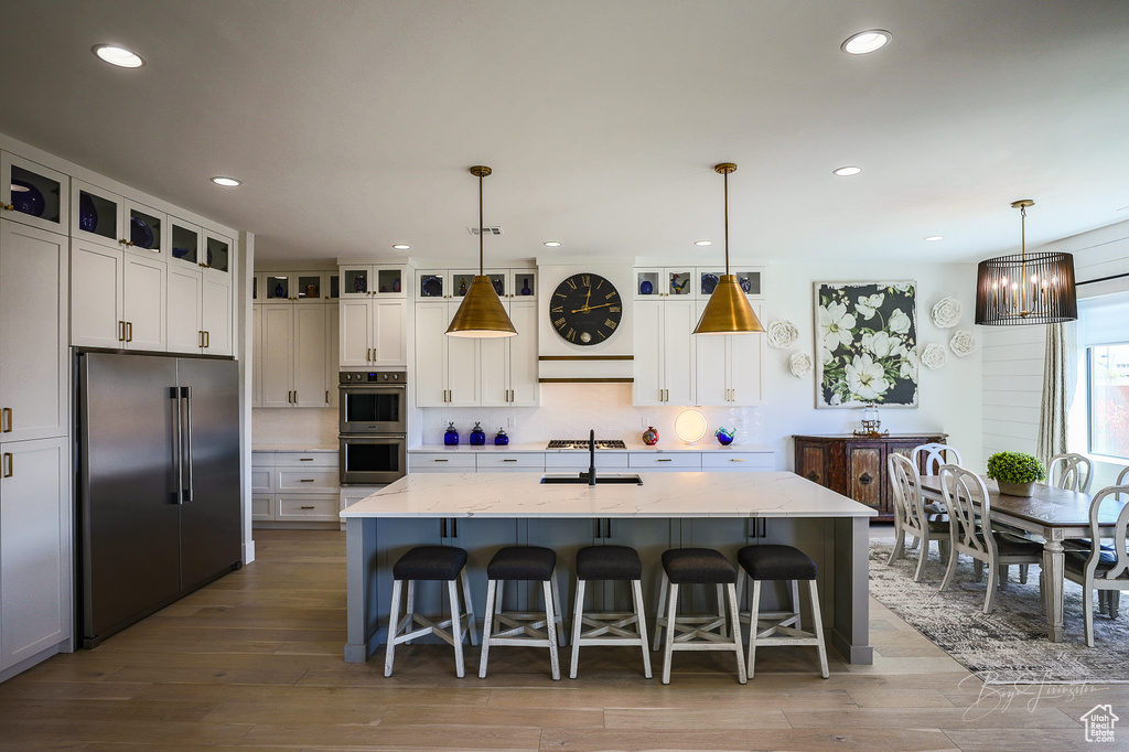 Kitchen featuring appliances with stainless steel finishes, hanging light fixtures, and white cabinetry