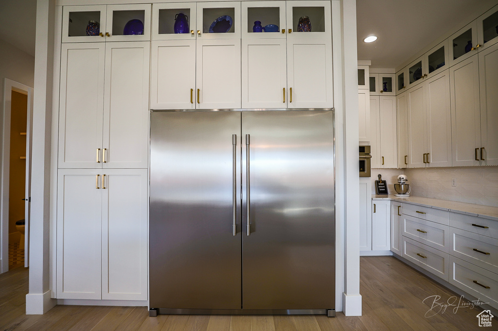 Kitchen featuring white cabinets, light hardwood / wood-style floors, and stainless steel built in fridge