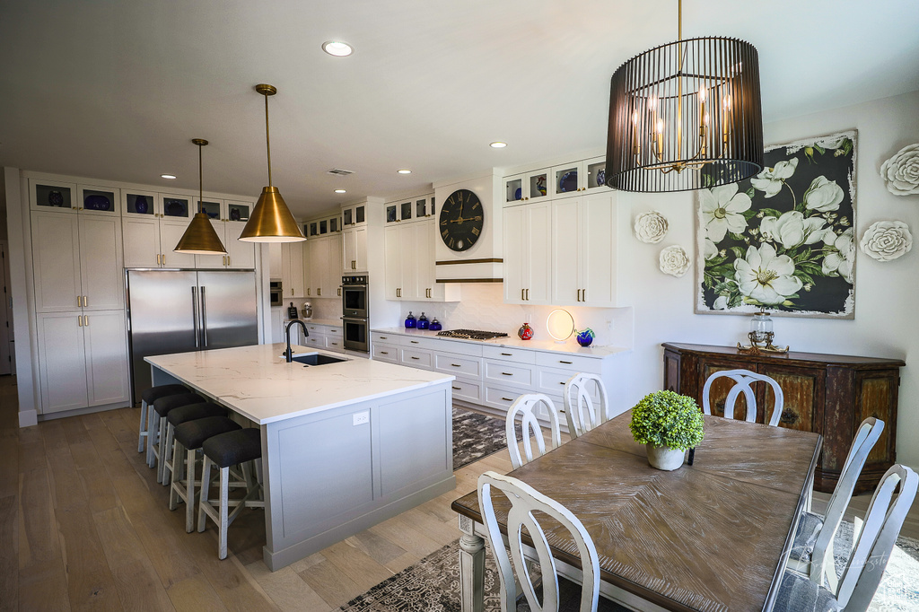 Kitchen featuring hanging light fixtures, light hardwood / wood-style flooring, a center island with sink, stainless steel appliances, and white cabinetry