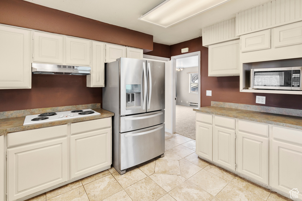 Kitchen with light carpet, white cabinetry, a baseboard radiator, and stainless steel appliances