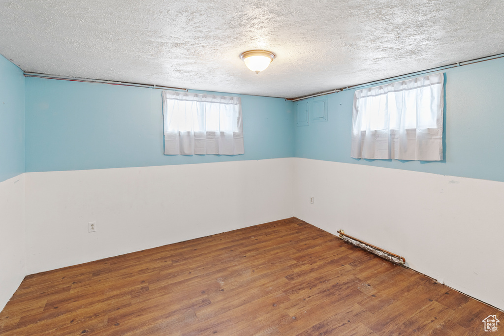 Empty room with plenty of natural light, hardwood / wood-style floors, and a textured ceiling