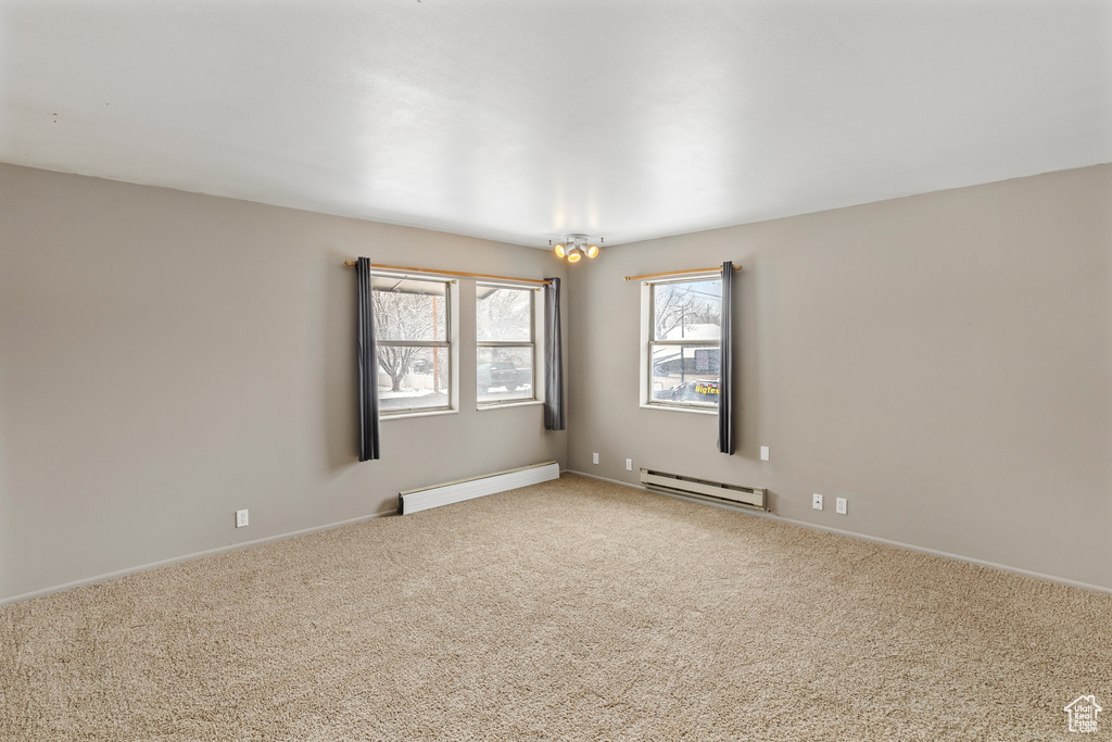 Spare room featuring light carpet and a baseboard heating unit