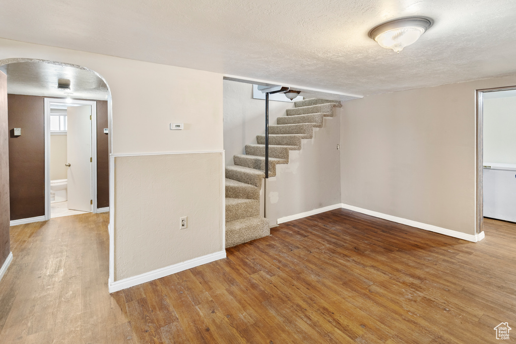 Basement featuring a textured ceiling and hardwood / wood-style flooring
