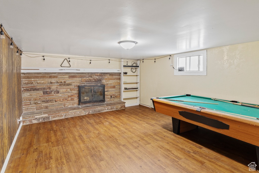 Rec room featuring billiards, a stone fireplace, and light hardwood / wood-style flooring