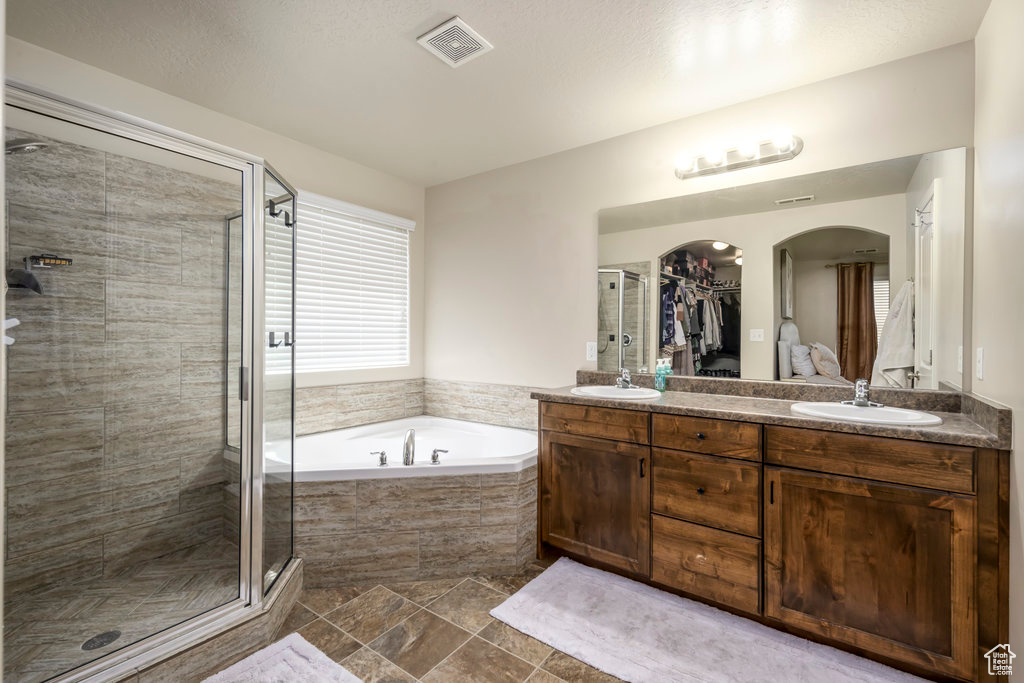Bathroom with dual sinks, tile floors, plus walk in shower, and oversized vanity