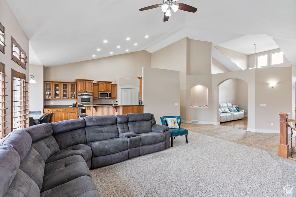 Living room featuring ceiling fan, light carpet, and high vaulted ceiling