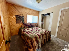Bedroom with wood walls and dark colored carpet