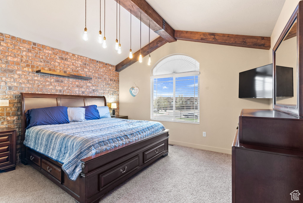 Carpeted bedroom featuring lofted ceiling with beams and brick wall