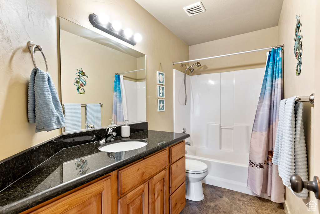 Full bathroom featuring tile flooring, shower / bath combination with curtain, toilet, and vanity