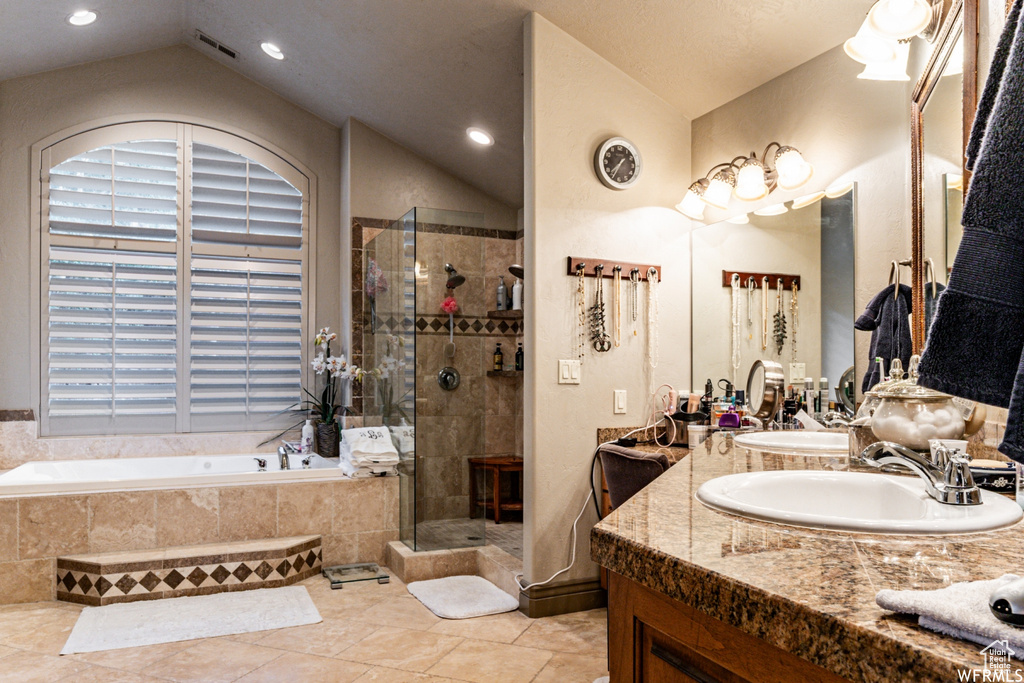 Bathroom with tile floors, vaulted ceiling, separate shower and tub, and vanity with extensive cabinet space