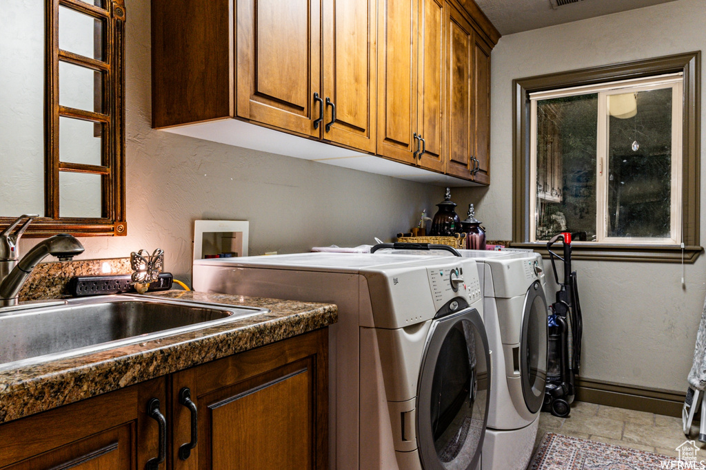 Washroom featuring light tile flooring, cabinets, hookup for a washing machine, washer and clothes dryer, and sink