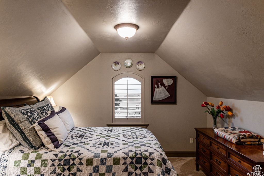 Bedroom featuring carpet floors, vaulted ceiling, and a textured ceiling