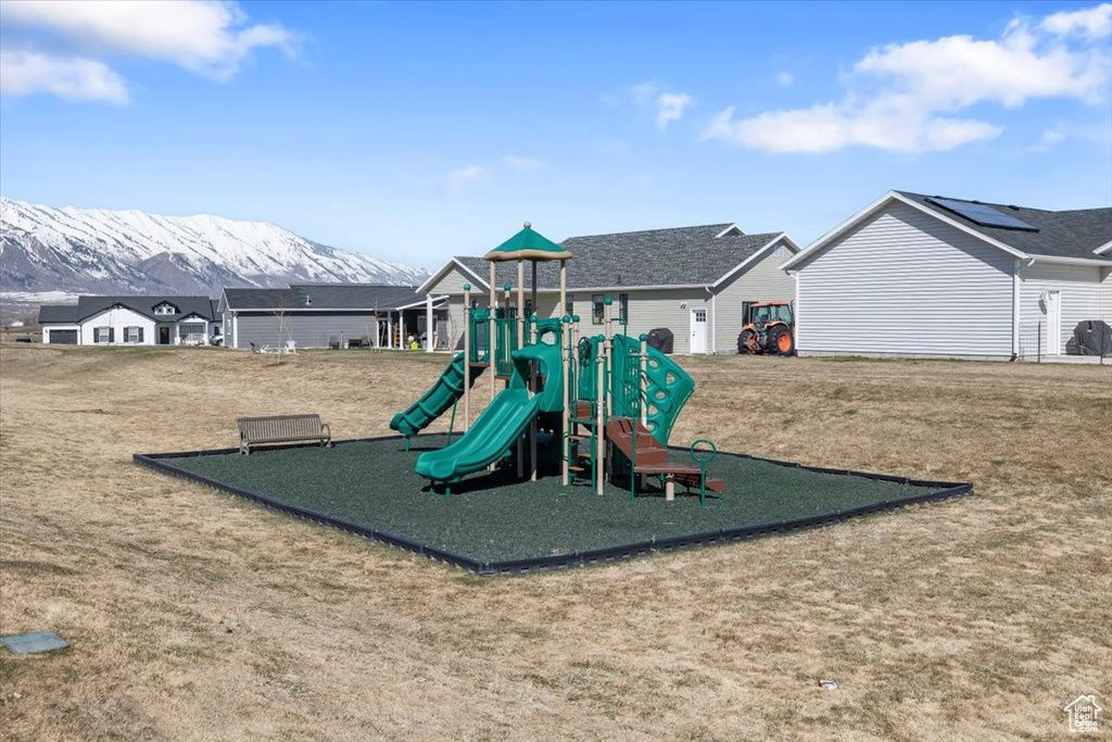 View of playground with a mountain view and a lawn