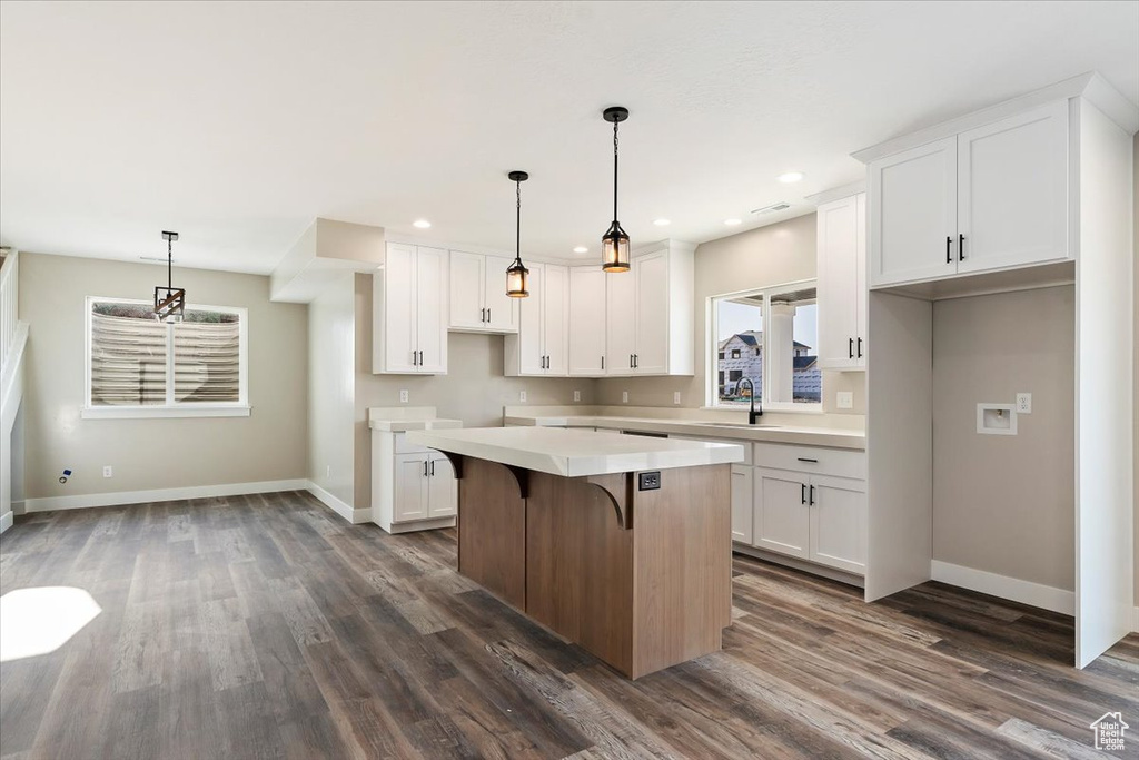 Kitchen featuring white cabinets, hanging light fixtures, and a kitchen island