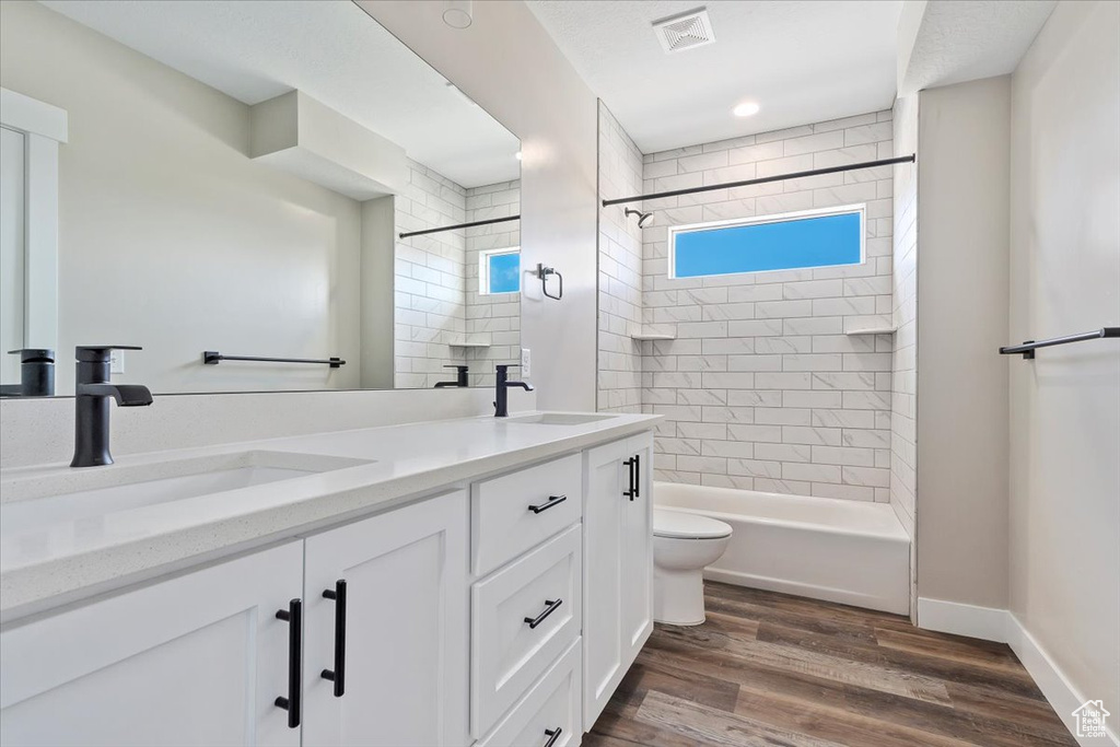 Full bathroom featuring toilet, hardwood / wood-style floors, vanity, and tiled shower / bath