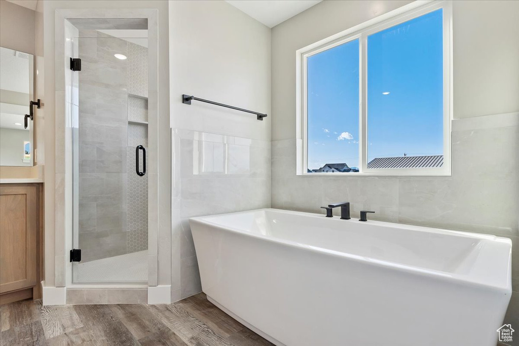 Bathroom featuring plus walk in shower, hardwood / wood-style flooring, and tile walls