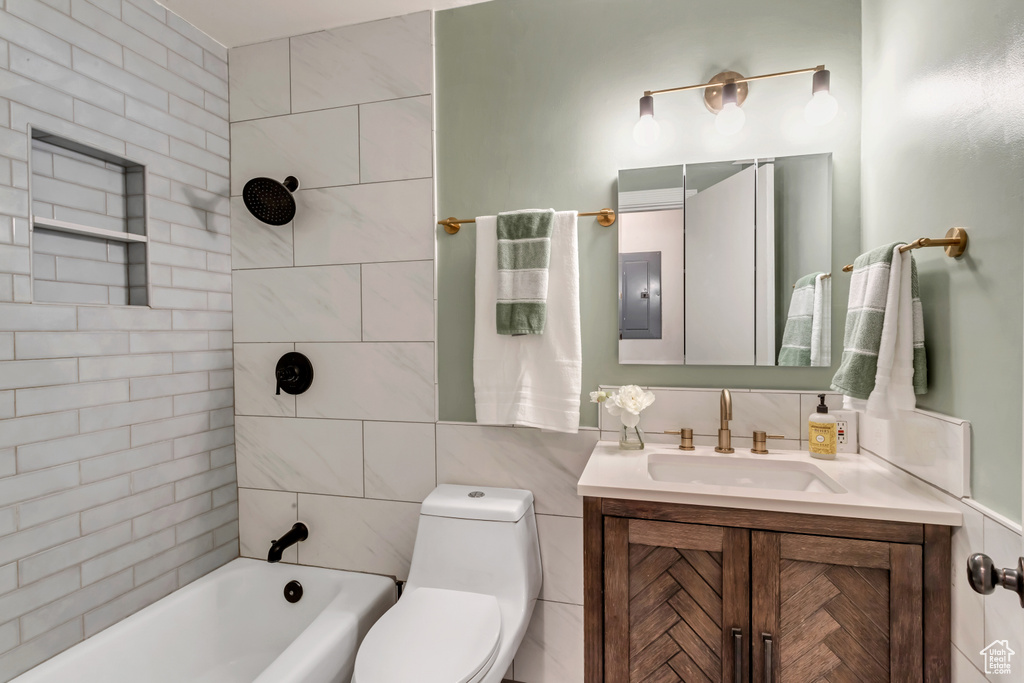 Full bathroom with tiled shower / bath, toilet, oversized vanity, and tile walls