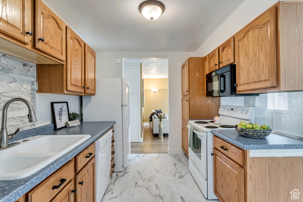 Kitchen with white appliances, sink, tasteful backsplash, and light tile floors