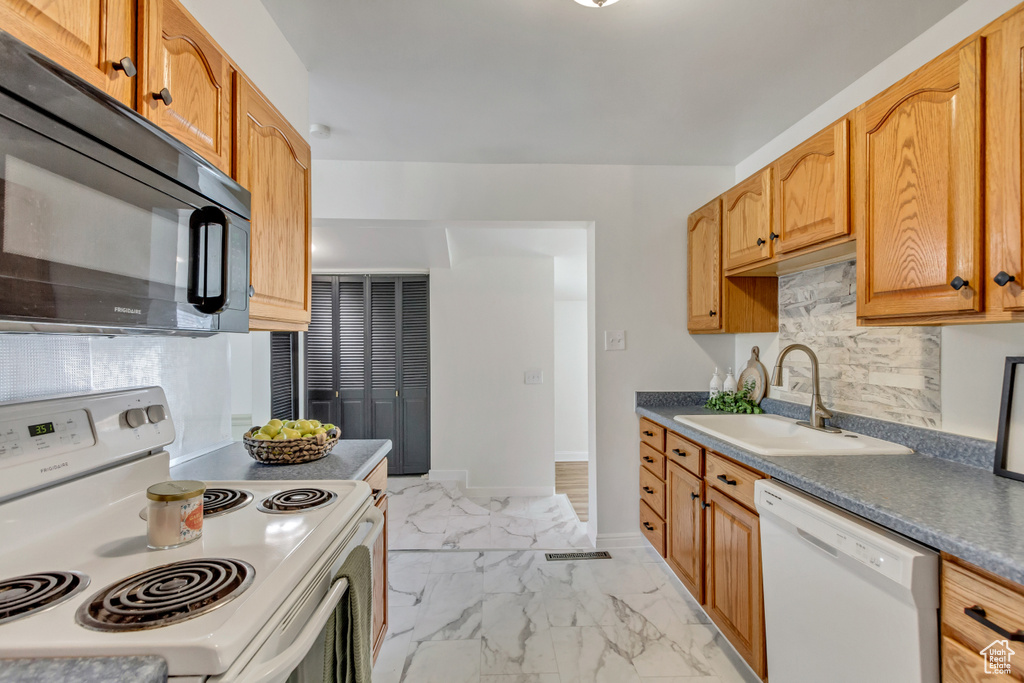 Kitchen with tasteful backsplash, white appliances, sink, and light tile floors