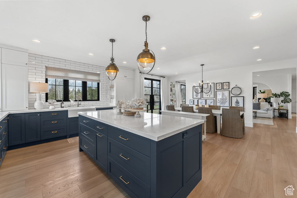 Kitchen with light hardwood / wood-style flooring, pendant lighting, sink, and a kitchen island
