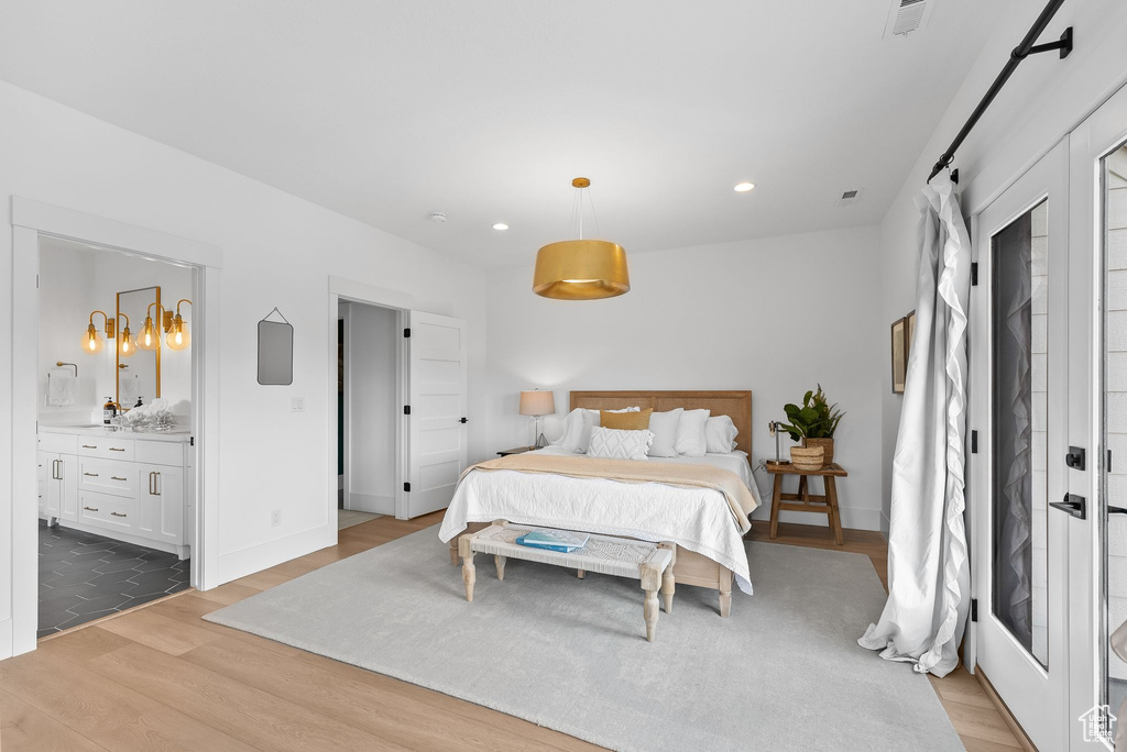 Bedroom with connected bathroom and light hardwood / wood-style floors