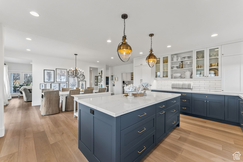 Kitchen featuring white cabinetry, light wood-type flooring, tasteful backsplash, and pendant lighting