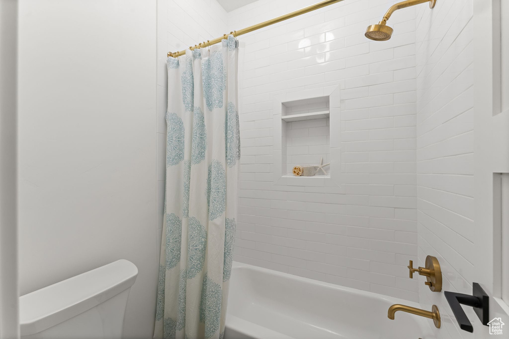 Bathroom featuring shower / bathtub combination with curtain and toilet