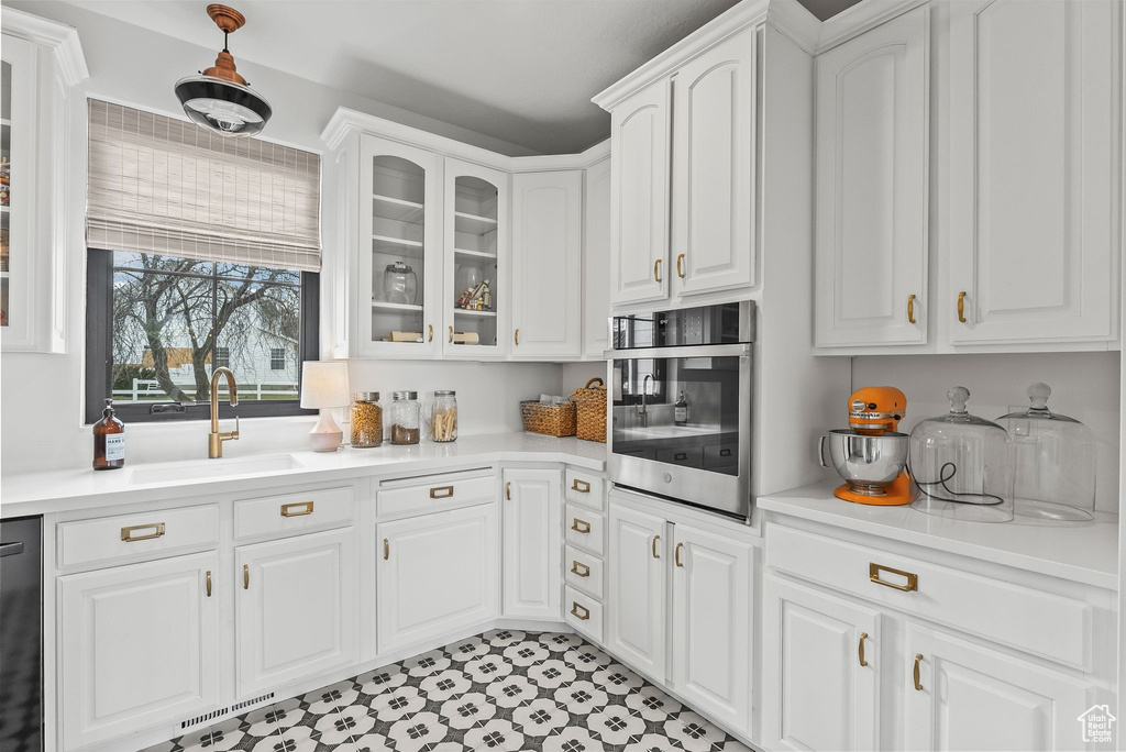 Kitchen featuring white cabinetry, light tile floors, dishwasher, sink, and oven