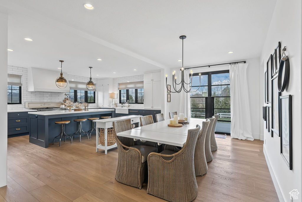 Dining area with light hardwood / wood-style flooring, a healthy amount of sunlight, a notable chandelier, and sink
