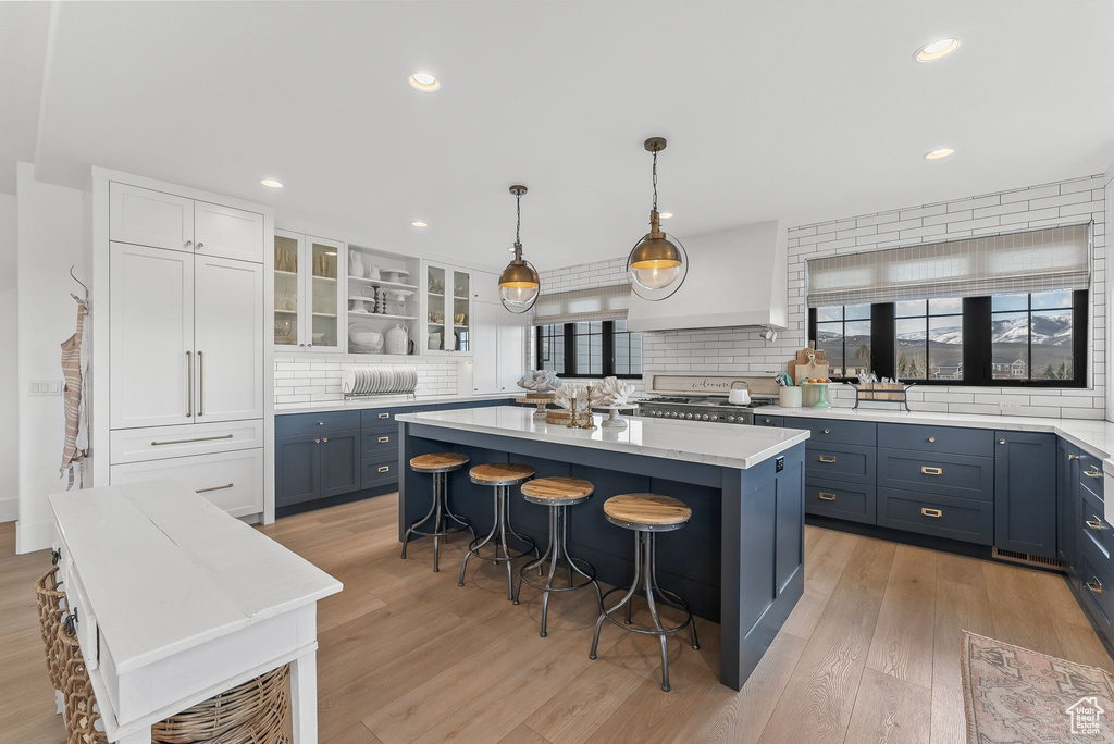 Kitchen featuring pendant lighting, a kitchen breakfast bar, a center island, tasteful backsplash, and light hardwood / wood-style flooring