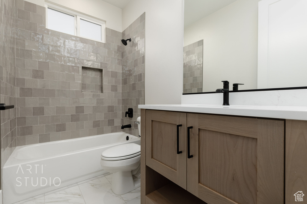 Full bathroom featuring vanity with extensive cabinet space, tiled shower / bath, toilet, and tile flooring