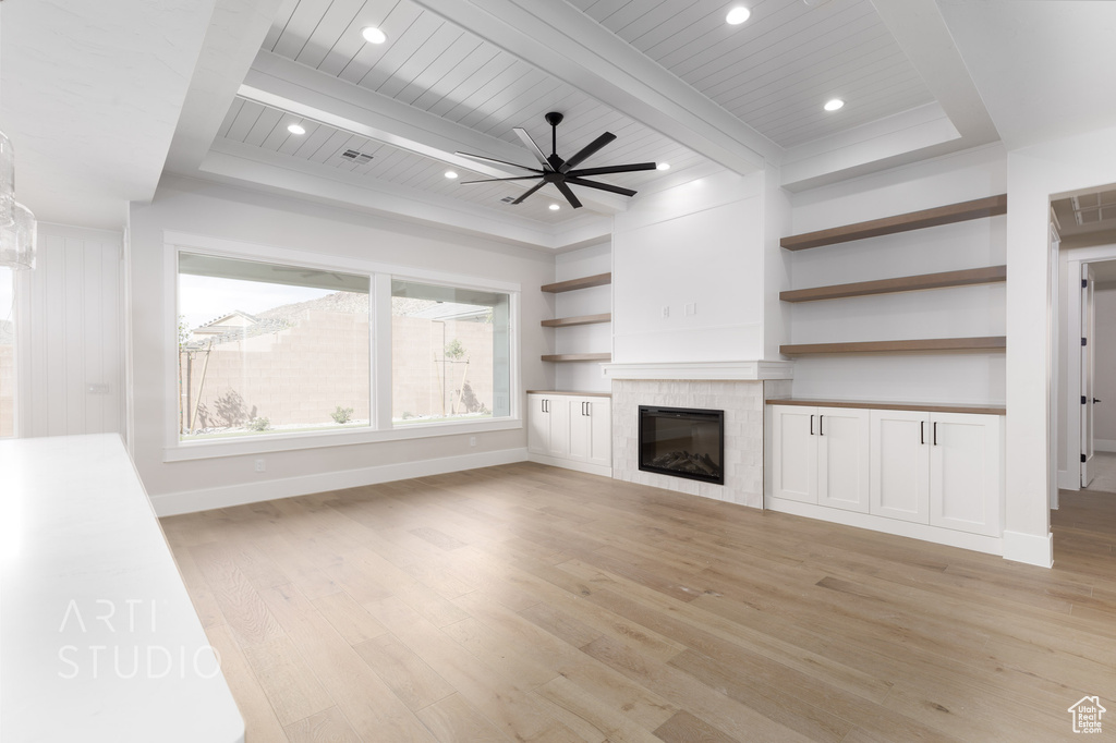 Unfurnished living room featuring light hardwood / wood-style flooring, ceiling fan, wood ceiling, beamed ceiling, and a fireplace