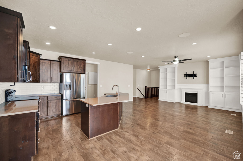 Kitchen with ceiling fan, a center island with sink, appliances with stainless steel finishes, sink, and dark hardwood / wood-style flooring
